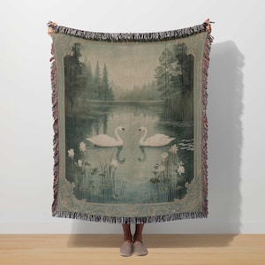 a woman holding a tapestry with swans on it
