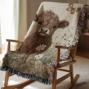 A brown cow with a flower on its back is sitting on a wooden rocking chair, which is covered with a blanket featuring a floral pattern.