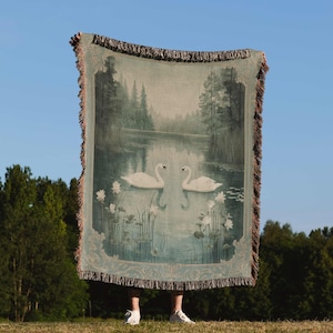 a person holding a large tapestry with swans on it