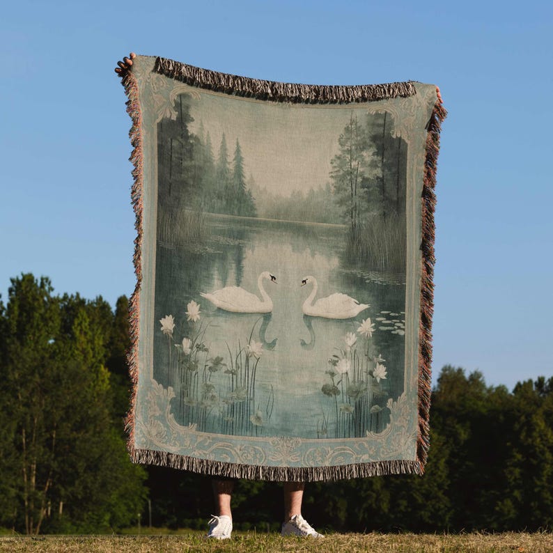 a person holding a large tapestry with swans on it