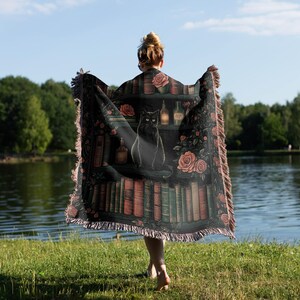 a woman holding a blanket with a cat on it