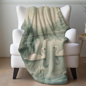 a blanket with a picture of two swans on a lake