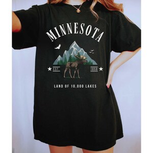 a woman wearing a black minnesota land of 10, 000 lakes t - shirt
