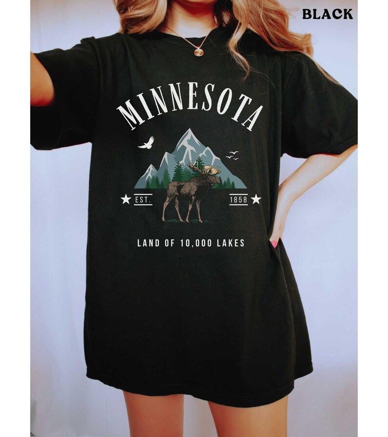 a woman wearing a black minnesota land of 10, 000 lakes t - shirt