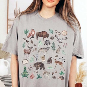 a woman wearing a grey t - shirt with animals on it