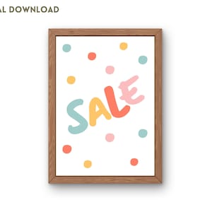 以下が含まれることがあります： 白い背景にカラフルなドットが散りばめられた、カラフルな文字で「SALE」と書かれた額装された印刷物。