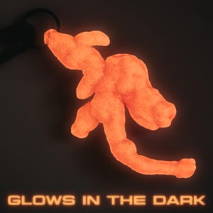 May include: An orange, abstract-shaped keychain glows in the dark. The keychain is attached to a black ring. The words "GLOWS IN THE DARK" are displayed in orange text at the bottom of the image.