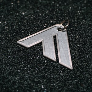 Può includere: Un portachiavi in metallo bianco a forma di freccia con un anello argentato.