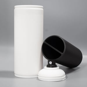 May include: Two spray paint cans, one white and one black. The black can is lying on its side with the lid off. The white can is standing upright.