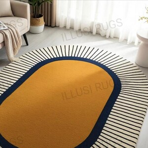 May include: Oval area rug with a mustard yellow center, a navy blue border, and a white background with black vertical stripes. The rug is a modern home decor item.