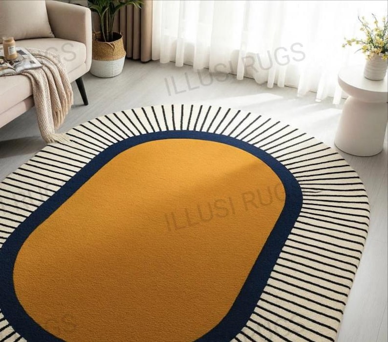 May include: Oval area rug with a mustard yellow center, a navy blue border, and a white background with black vertical stripes. The rug is a modern home decor item.