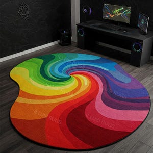 Puede incluir: Una alfombra redonda abstracta y colorida con un diseño de arcoíris. La alfombra tiene forma de óvalo y tiene un borde negro. La alfombra está hecha de un material suave y mullido y es perfecta para agregar un toque de color a cualquier habitación.