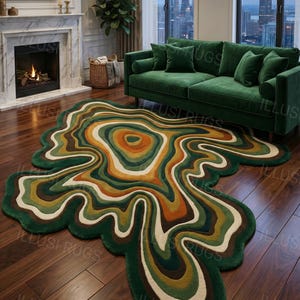 May include: A unique, abstract area rug with a flowing, organic design. The rug features concentric bands of green, brown, orange, and cream colors, creating a visually striking pattern. It's placed on a hardwood floor in a living room setting.