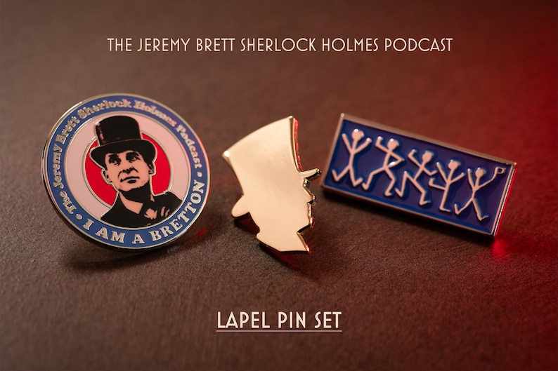 Pu&ograve; includere: Un set di tre spille da bavero che include una spilla circolare con il ritratto di un uomo con cilindro e il testo "The Jeremy Brett Sherlock Holmes Podcast" e "I AM A BRETTON", una spilla dorata a forma di cilindro e una spilla rettangolare blu.
