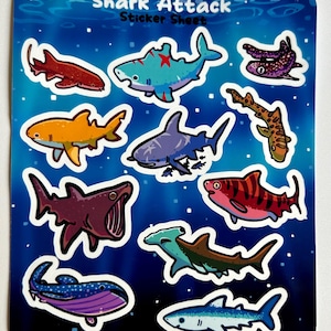 May include: A sticker sheet with a blue background and stars. The sheet features 10 different shark stickers, including a hammerhead shark, a whale shark, and a tiger shark. The text "Shark Attack Sticker Sheet" is at the top of the sheet.
