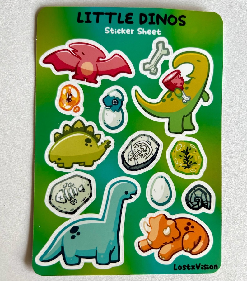 Op de afbeelding: Een stickerblad met een groene achtergrond met verschillende dinosaurus illustraties. Het blad bevat een roze pterodactyl, een groene dinosaurus die een bot eet, een blauwe dinosaurus in een ei, een groene stegosaurus, een blauwe brachiosaurus, een oranje triceratops en verschillende fossiele illustraties.