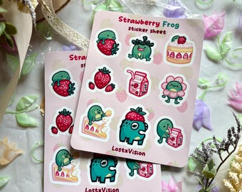 Op de afbeelding: Twee roze sticker vellen met aardbei kikker ontwerpen. Elke vel bevat verschillende stickers, waaronder aardbeien, kikkers en een taart. De tekst "Strawberry Frog sticker sheet" en "LostxVision" zijn zichtbaar.