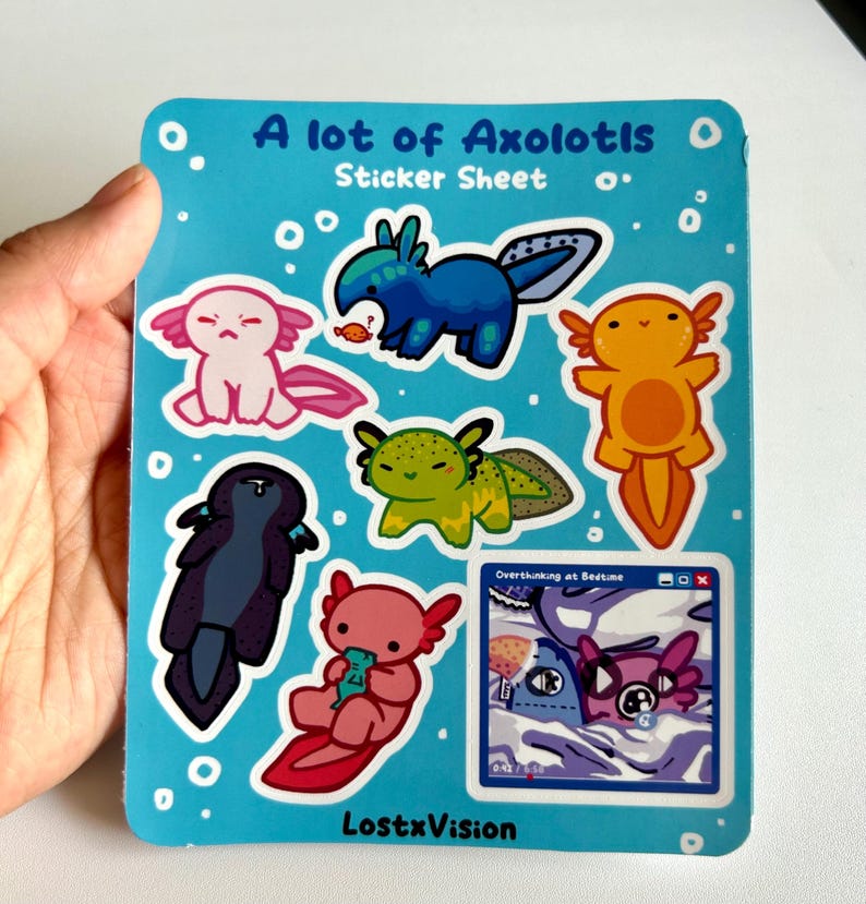 May include: A sticker sheet titled "A lot of Axolotls Sticker Sheet". The sheet features nine colourful axolotl stickers with different poses and expressions. The stickers are on a blue background with white bubbles. One sticker shows an axolotl with the text "Oversleeping at Bedtime" in a blue computer window.