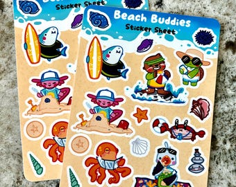 May include: A sticker sheet with a beach theme featuring various cartoon characters, including a shark surfing, an axolotl building a sandcastle, a turtle wearing sunglasses, and an octopus reading a book. The sticker sheet is titled "Beach Buddies Sticker Sheet" and has a blue and white wave design.