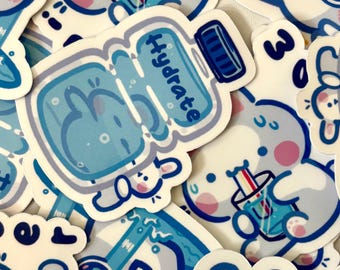 May include: A collection of stickers featuring cute cartoon bunnies drinking from blue and white cups with straws. The stickers also include a blue and white water bottle with the word "Hydrate" on it.