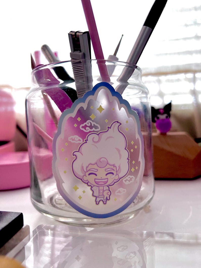 May include: A glass jar with a holographic sticker of a cartoon character with white hair, a pink shirt, and a blue background. The sticker has a cloud and star design.
