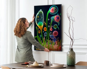 May include: A woman hangs a framed abstract art print on a white wall. The print features a colorful, organic design with green, yellow, blue, and red hues. The print is framed in black.