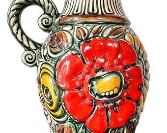 May include: A ceramic vase with a handle, featuring a vibrant red flower design. The vase has a green and cream color scheme, with intricate floral and leaf patterns. The vase is approximately 10 inches tall.