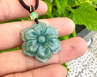 Grade A jadeite pendant, hand-carved in the shape of a flower. Youth and fashion. Made of raw materials on a blue background.
