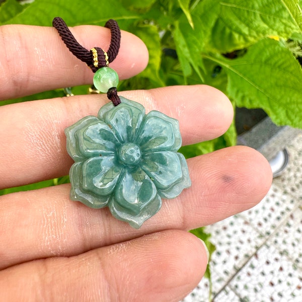 Grade A jadeite pendant, hand-carved in the shape of a flower. Youth and fashion. Made of raw materials on a blue background.