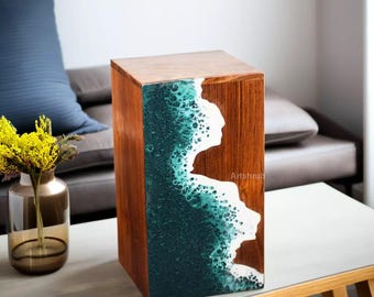 May include: A wooden side table with a teal and white resin wave design. The table is made of dark wood and has a square top.