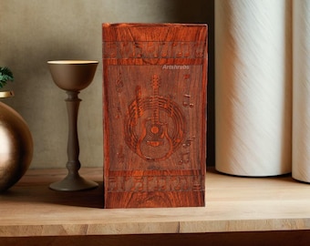 May include: A wooden box with a carved guitar and musical notes design. The box is a dark reddish brown color and has a smooth finish.
