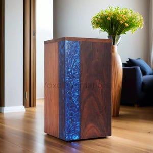 Puede incluir: Una mesa auxiliar de madera con una incrustación de resina azul. La mesa está hecha de madera oscura y tiene un diseño moderno.