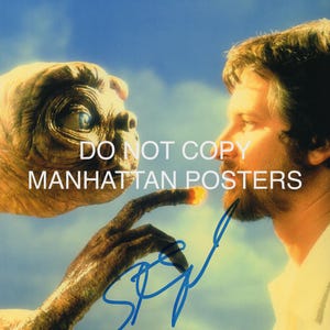 Könnte beinhalten: Ein Filmplakat mit E.T. dem Außerirdischen und einem Mann. E.T. hat einen langen Finger, der den Bart des Mannes berührt. Das Plakat trägt den Text "DO NOT COPY MANHATTAN POSTERS" und eine blaue Unterschrift. Der Hintergrund ist ein blauer Himmel.