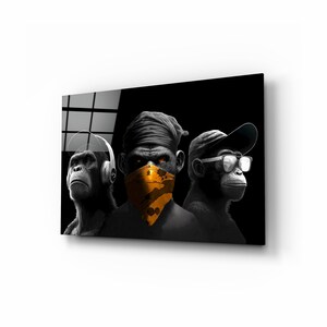 May include: A black and white digital art print featuring three chimpanzees. One wears headphones, another a bandana, and the third a cap and glasses. The bandana is orange with black paint splatters. The chimpanzees have glowing orange eyes.