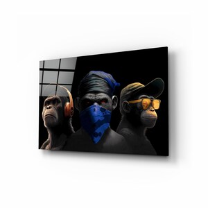 May include: A framed art print featuring three chimpanzees with distinct accessories. One wears headphones, another a blue bandana, and the third a cap and sunglasses. The artwork has a dark background and a modern, edgy aesthetic.