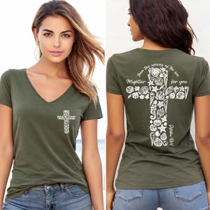 May include: Olive green V-neck t-shirt featuring a white cross design on the front and back. The cross is composed of various seashell illustrations. The back of the shirt has the text "Than the waves of the sea mightier for you" and "Psalm 93:4".