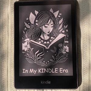 May include: A black and white illustration of a woman reading a book on a Kindle e-reader. The illustration is surrounded by flowers and leaves. The text on the screen reads "In My Kindle Era".