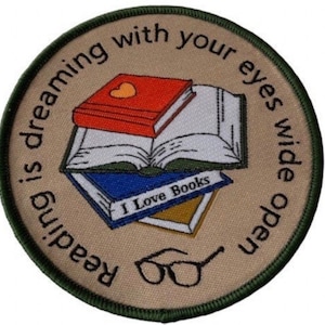 May include: Circular patch with a green trim and a beige background. It depicts three books, one red with a heart, one open, and one blue with "I Love Books." The text around the edge says "Reading is dreaming with your eyes wide open." A pair of spectacles is at the bottom.