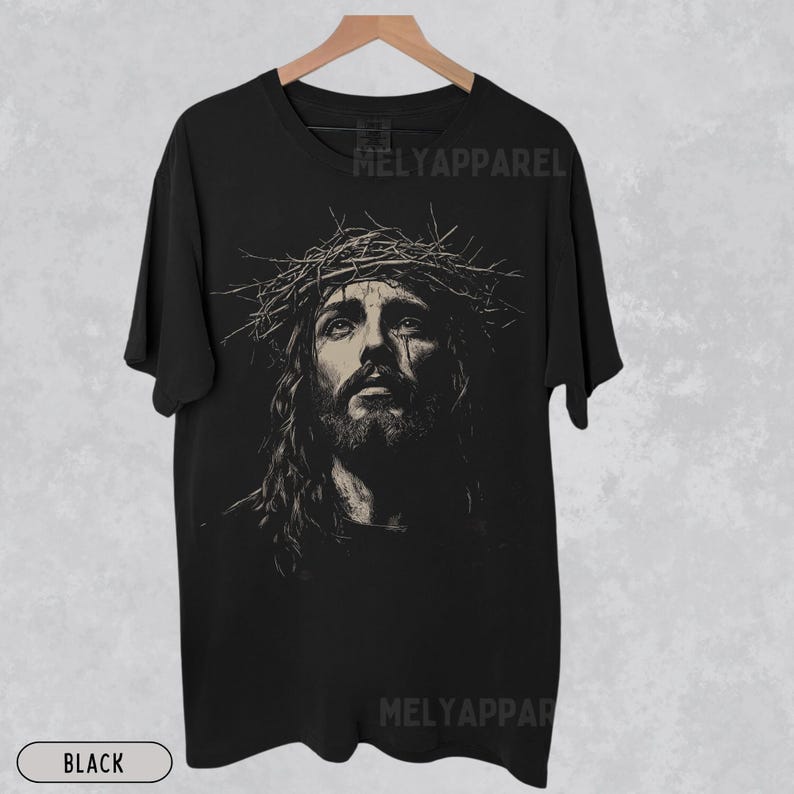 May include: Black t-shirt featuring a sepia-toned portrait of Jesus wearing a crown of thorns. The image is centered on the shirt, with the text "MELYAPParel" printed at the top and bottom. The word "BLACK" is printed at the bottom.