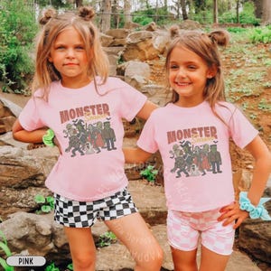 May include: Two light pink short-sleeved t-shirts featuring a graphic print of various classic monsters and the text "MONSTER Season". The shirts are paired with black and white checkered shorts and light pink and white checkered shorts respectively.