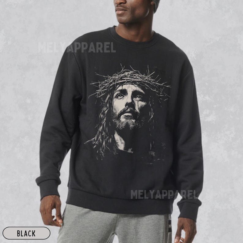 May include: Black sweatshirt featuring a detailed graphic of a man with long hair wearing a crown of thorns. The image has a vintage, artistic style. The text "MELY APPAREL" is printed on the top and bottom of the sweatshirt. The word "BLACK" is printed at the bottom.