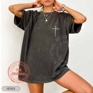 May include: Dark gray t-shirt with a cross design and the text "MELYAPParel". The shirt also features a circular design with the text "MELYAPParel" and a stamp that says "THE ORIGINAL". The word "PEPPER" is at the bottom.