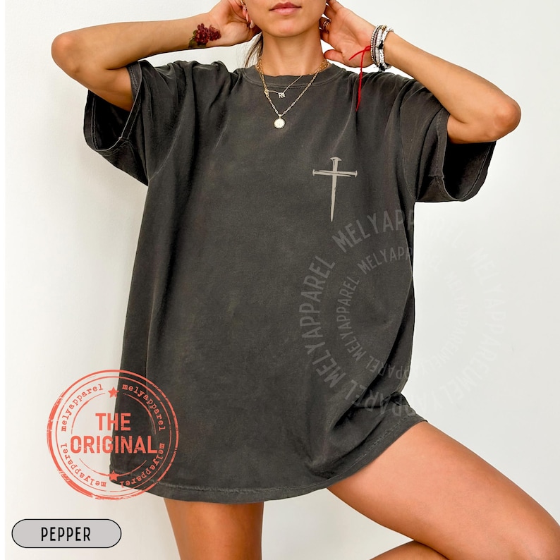 May include: Dark gray t-shirt with a cross design and the text "MELYAPParel". The shirt also features a circular design with the text "MELYAPParel" and a stamp that says "THE ORIGINAL". The word "PEPPER" is at the bottom.