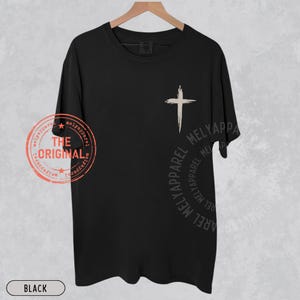May include: Black t-shirt with a white cross graphic on the front. The shirt has the text "THE ORIGINAL" and "MELYAPPAREL" printed on it. The word "BLACK" is printed at the bottom of the shirt.