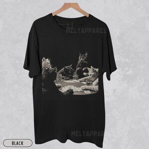 Puede incluir: Camiseta negra con un gr&aacute;fico en tonos sepia de gatos jugando al p&oacute;quer alrededor de una mesa. La imagen incluye vasos de whisky y naipes. El texto "MELYAPPAREL" est&aacute; impreso en la camiseta. La palabra "BLACK" est&aacute; impresa en la parte inferior.