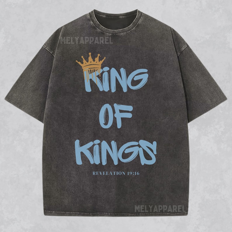 May include: A black t-shirt with a faded look features a gold crown and the text "King of Kings" in blue with a graffiti style font. The text "Revelation 19:16" is printed below the main text.