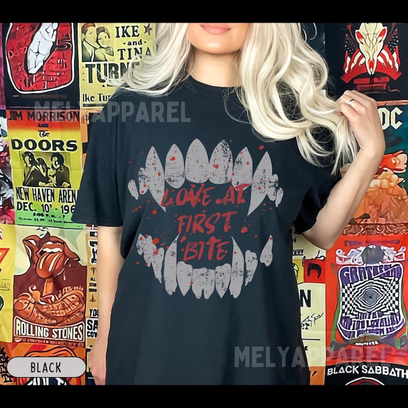 K&ouml;nnte beinhalten: Schwarzes T-Shirt mit einem Zahnmotiv und dem roten Schriftzug "LOVE AT FIRST BITE". Dieses Kleidungsst&uuml;ck ist f&uuml;r den l&auml;ssigen Stil geeignet und ein auff&auml;lliges Statement.