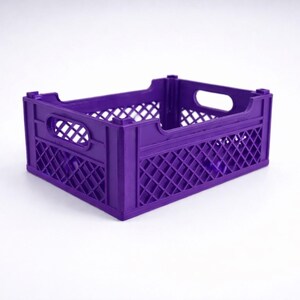 May include: A purple plastic crate with a rectangular form. The crate features a lattice design on its sides and a handle opening at each end. The crate is designed for storage and transport.