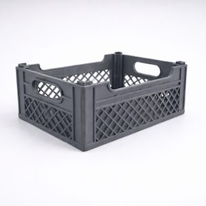 May include: A dark grey plastic crate with a rectangular form. The crate features a lattice pattern on its sides and oval-shaped handles. This storage container is suitable for various items.