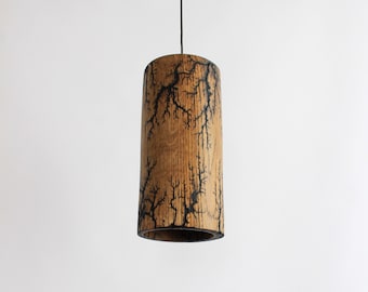 May include: A wooden pendant light with a cylindrical shade featuring a black lightning bolt pattern.